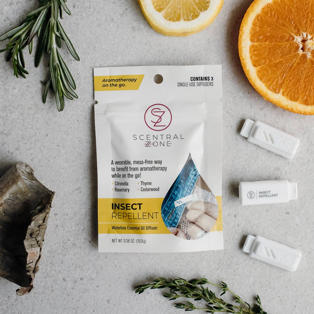 Scentral Zone aromatherapy insect repellent wearable diffuser packaging on a gray surface with herbs and oranges.